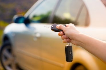 Mulher com chave na mão abrindo carro