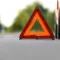Image of a red car stopped on the road, with safety signage, waiting for car insurance