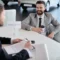 Two men in suits hold rental car documents at a car rental company.