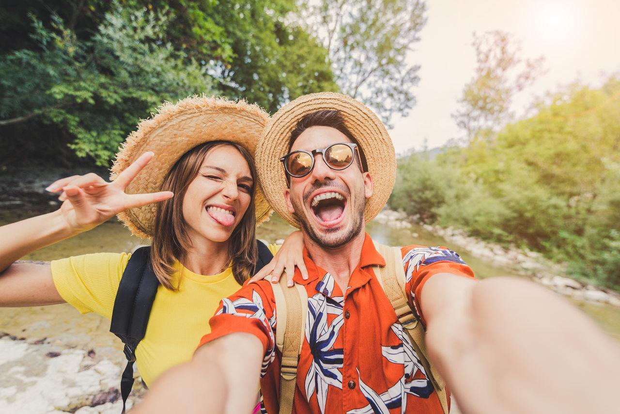 Um casal feliz, com roupas coloridas,tirando uma selfie em um lugar ao ar livre