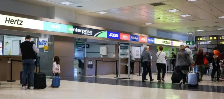Airport lobby with car rental company stores and people in line