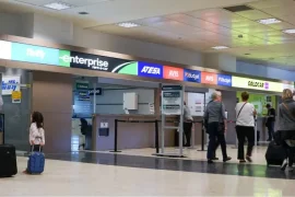 Airport lobby with car rental company stores and people in line