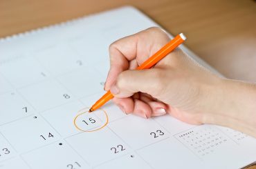 mão feminina circulando o número 15 em um calendário