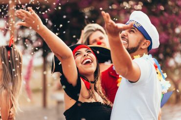 casal jogando confete no ar em uma festa de carnaval de rua