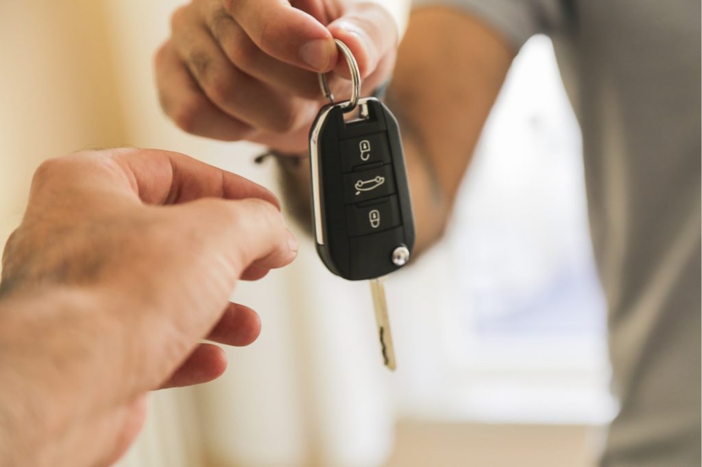Duas pessoas trocam uma chave de carro para fechar negócios