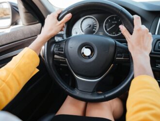 mãos femininas segurando o volante de um carro