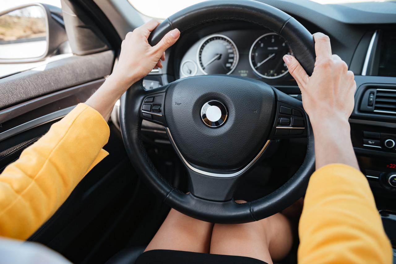 mãos femininas segurando o volante de um carro
