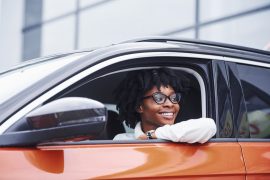 woman inside driver's side of an orange car