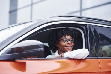 woman inside driver's side of an orange car