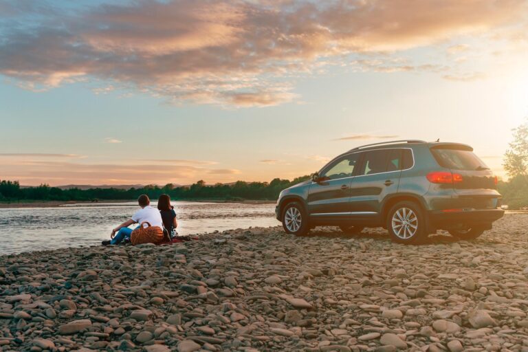 couple with dog by the lake with a car parked