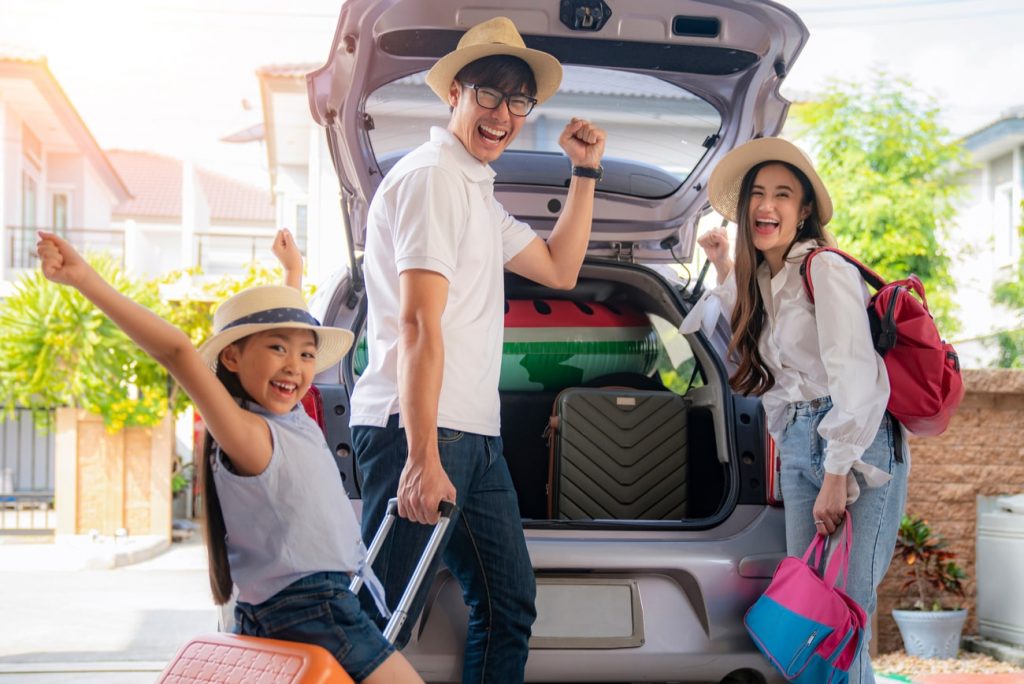 família animada colocando malas dentro do carro para viajar