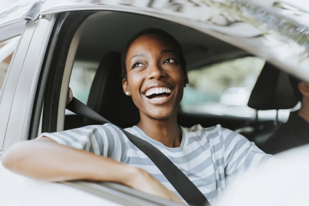 Mulher sorrindo dentro do carro depois de alugar um carro para viajar com a Rentcars.