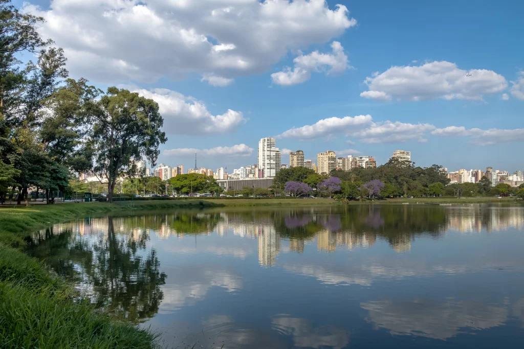 Foto do Parque Ibirapuera em São Paulo, com lago, mata verde e céu azul.