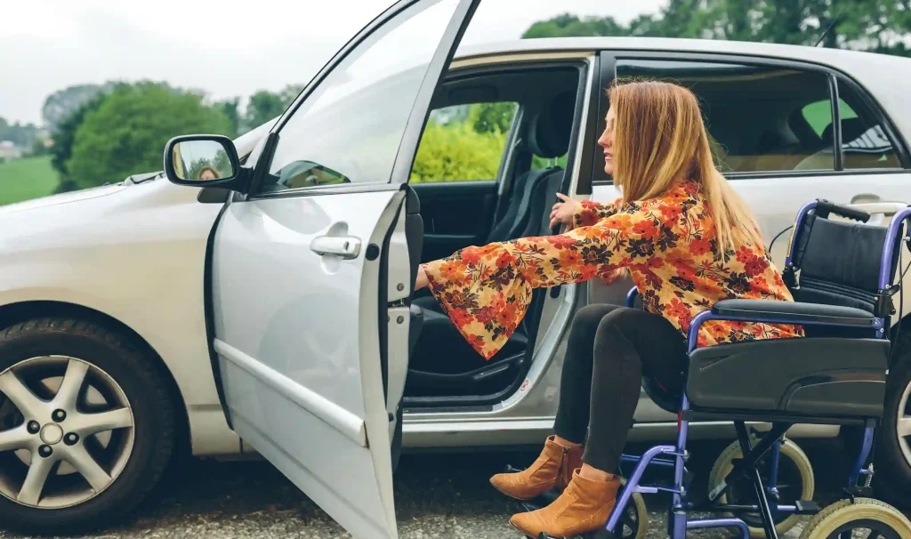 Mujer en silla de ruedas que se dispone a entrar en un auto adaptado