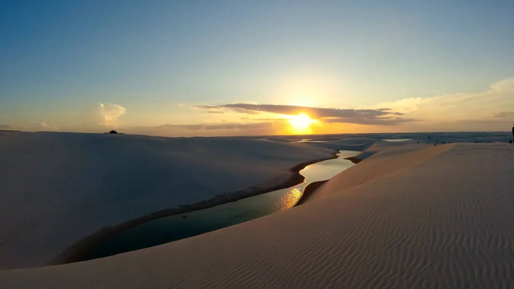 Parque Nacional dos Lençóis Maranhenses visto de cima, ao pôr-do-sol, com as lagoas de água azul cercadas pelas dunas de areia.