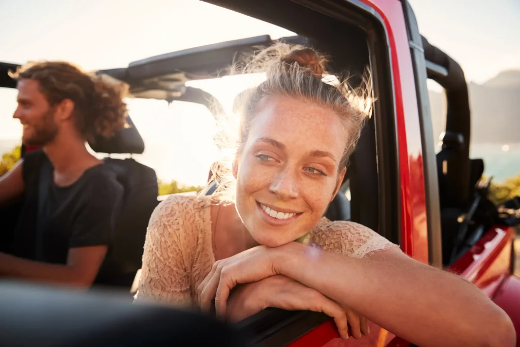 Foto de uma mulher na janela do carro sorrindo para foto. 