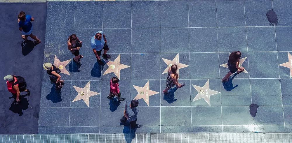 Foto de cima de pessoas andando sobre as estrelas da Calçada da Fama.