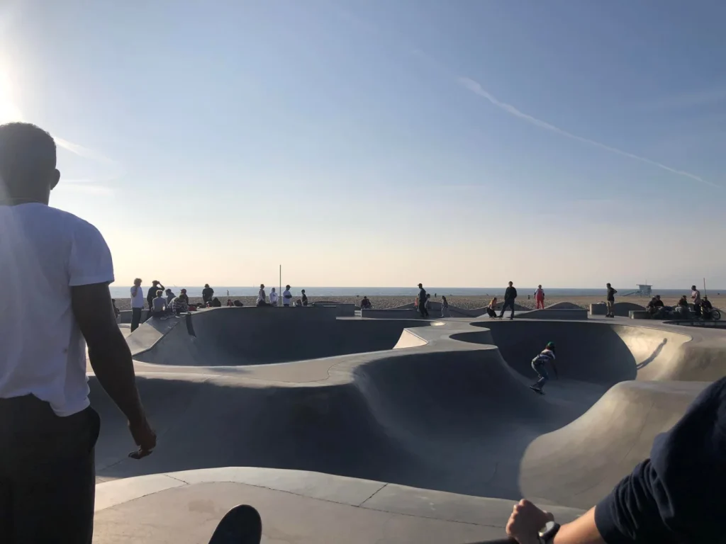 Foto da pista de skate super famosa de Venice Beach, com um fluxo grande de skatistas realizando manobras. 
