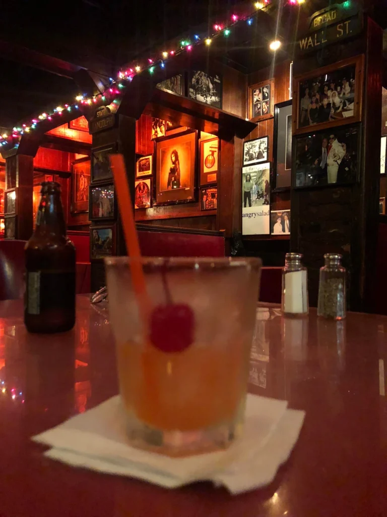 Foto de um dos drinks de cereja famosos do Rainbow, bar que é considerado um clássico do rock em Los Angeles. É possível ver quadros com cantores famosos ao fundo.