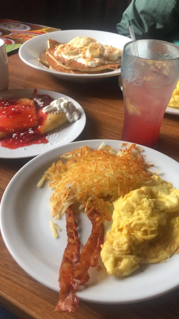 Café da manhã do Denny's em Los Angeles. A foto mostra um copo de suco de morango, panquecas, ovos e bacon.