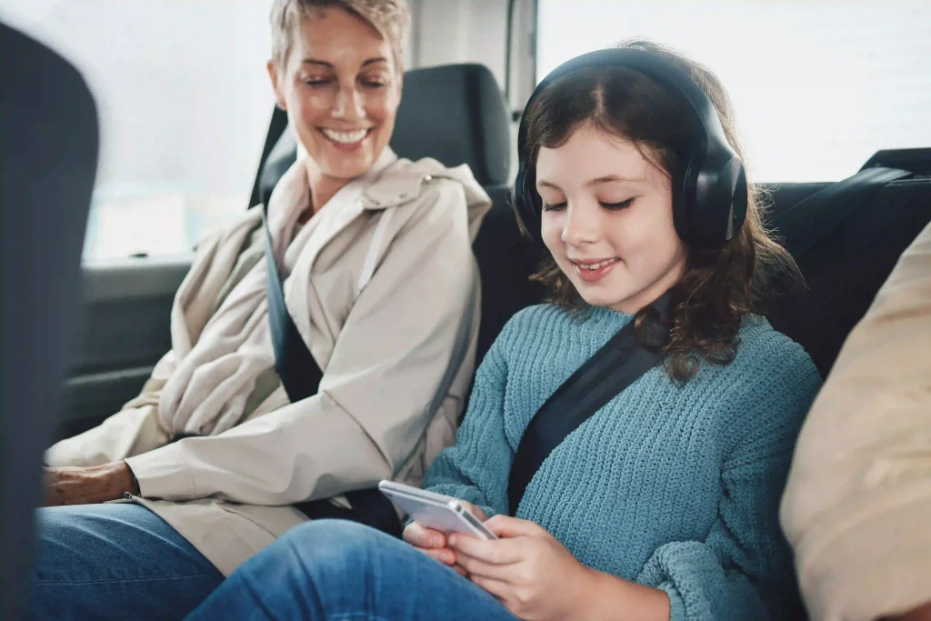 Una niña con su madre en un auto escuchando  música con sus auriculares
