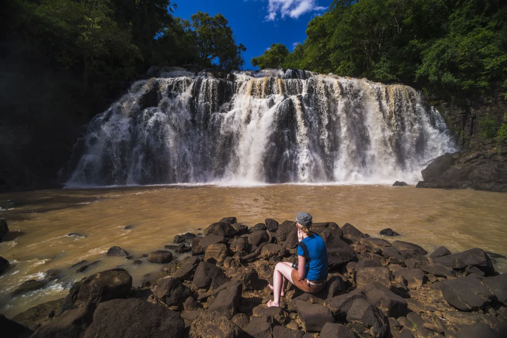 Foto de uma das belas cachoeiras de Puerto Iguazu, com uma turista observando a queda d'água.