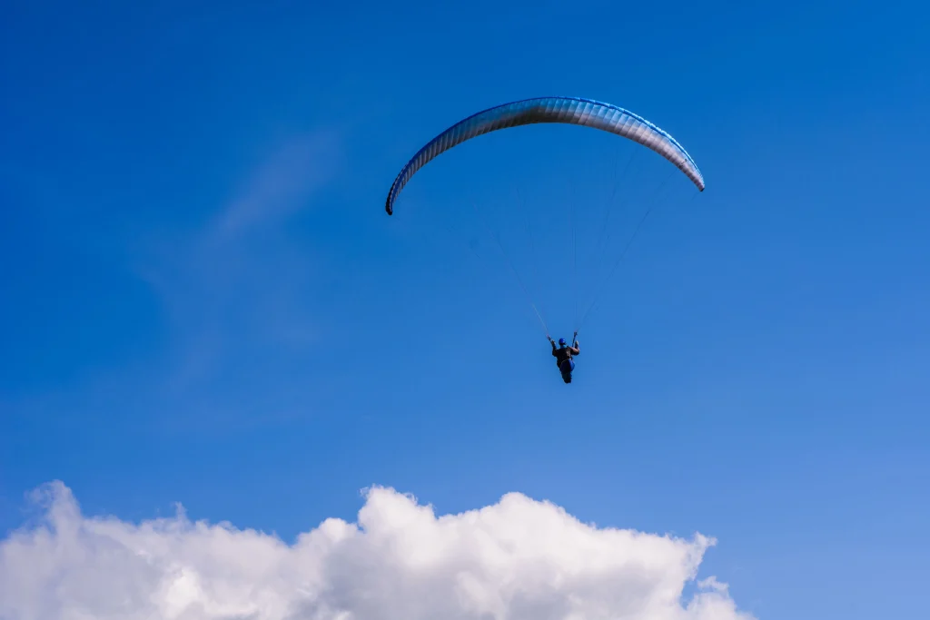 Imagem de um homem saltando de paraquedas com o céu azul ao fundo.