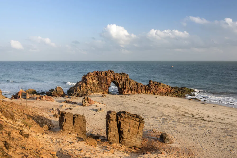 Foto da Pedra Furada em Jericoacoara, região Nordeste do Brasil. O mar e o céu estão na cor azul.