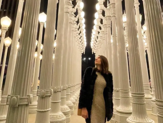 imagem de um salão com centenas de postes de luz brancos, com uma menina posando ao centro