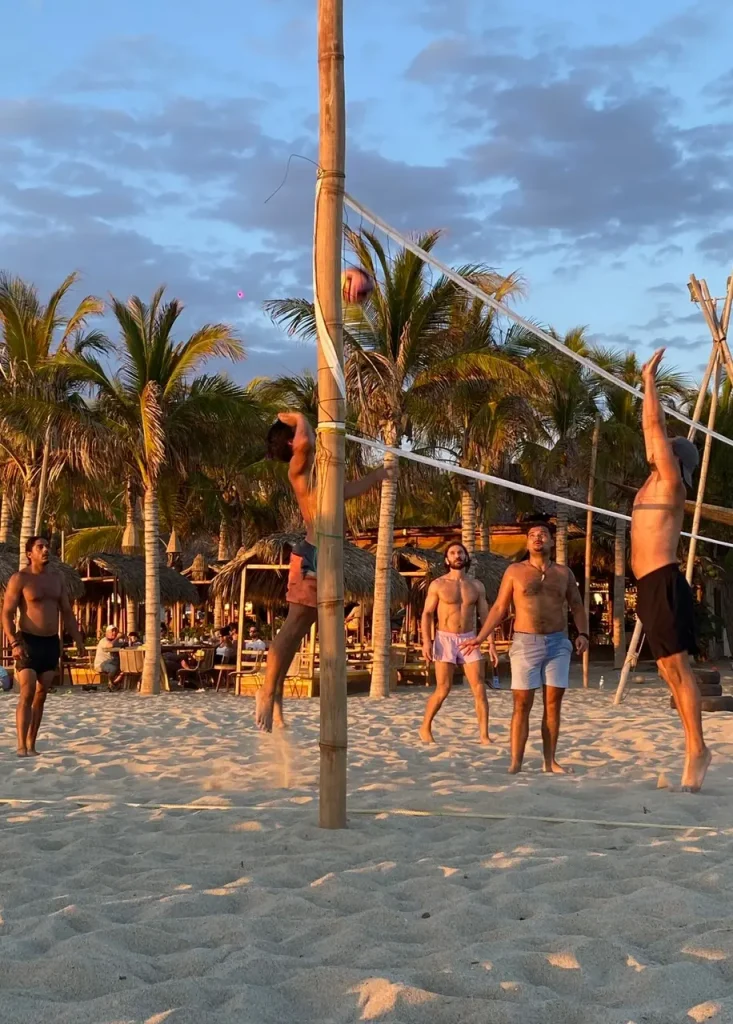 Cinco personas jugando beach volleyball en una de las canchas de Punta Zicatela (una de las mejores cosas que hacer en Puerto Escondido).