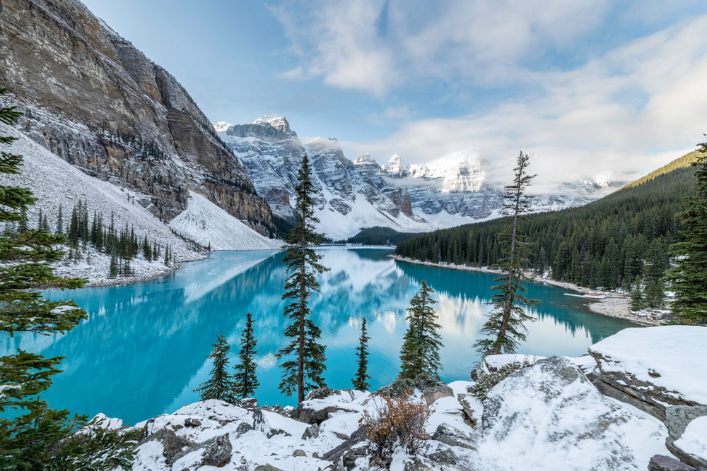 Foto incrível da região dos lagos do Canadá, os lagos são bem azuis e cristalinos com rochas repletas de neve em volta.