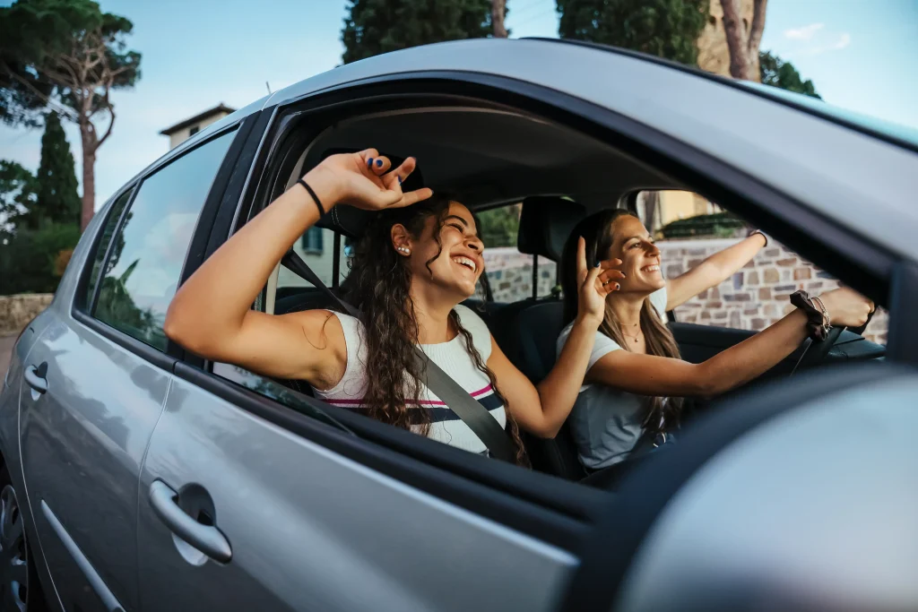 Dos chicas oyendo sus canciones de viaje al manejar en carretera