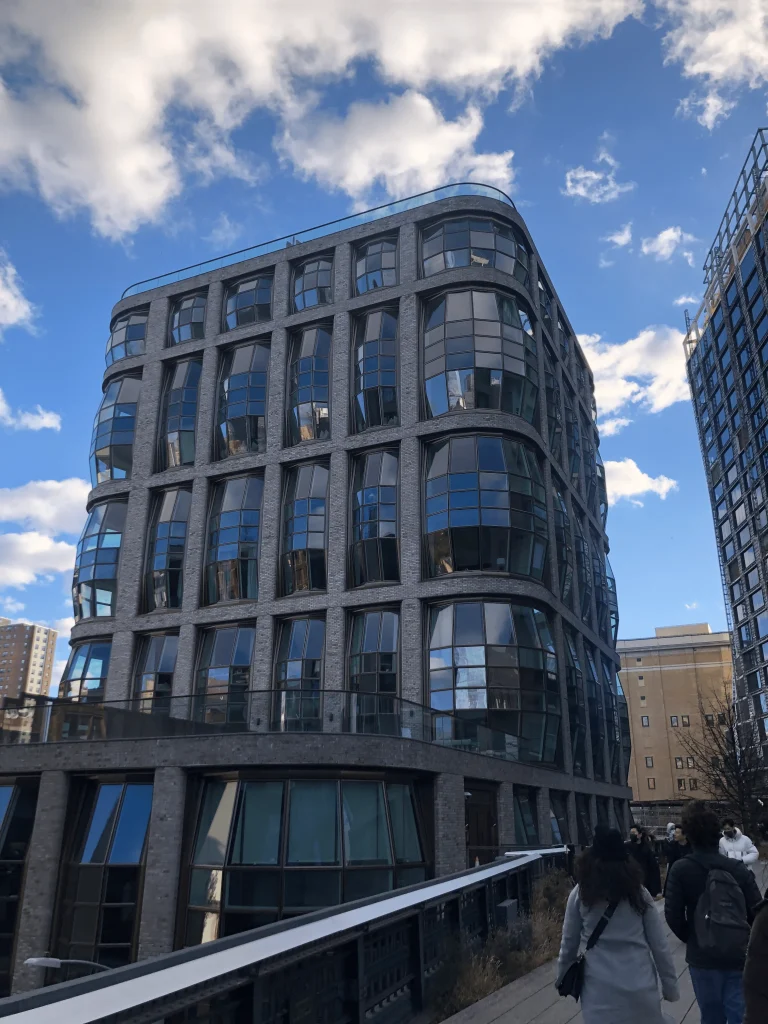 Foto de um dos prédios imponentes do High Line em New York. O prédio é moderno, com vidros em todos os andares em formato oval.