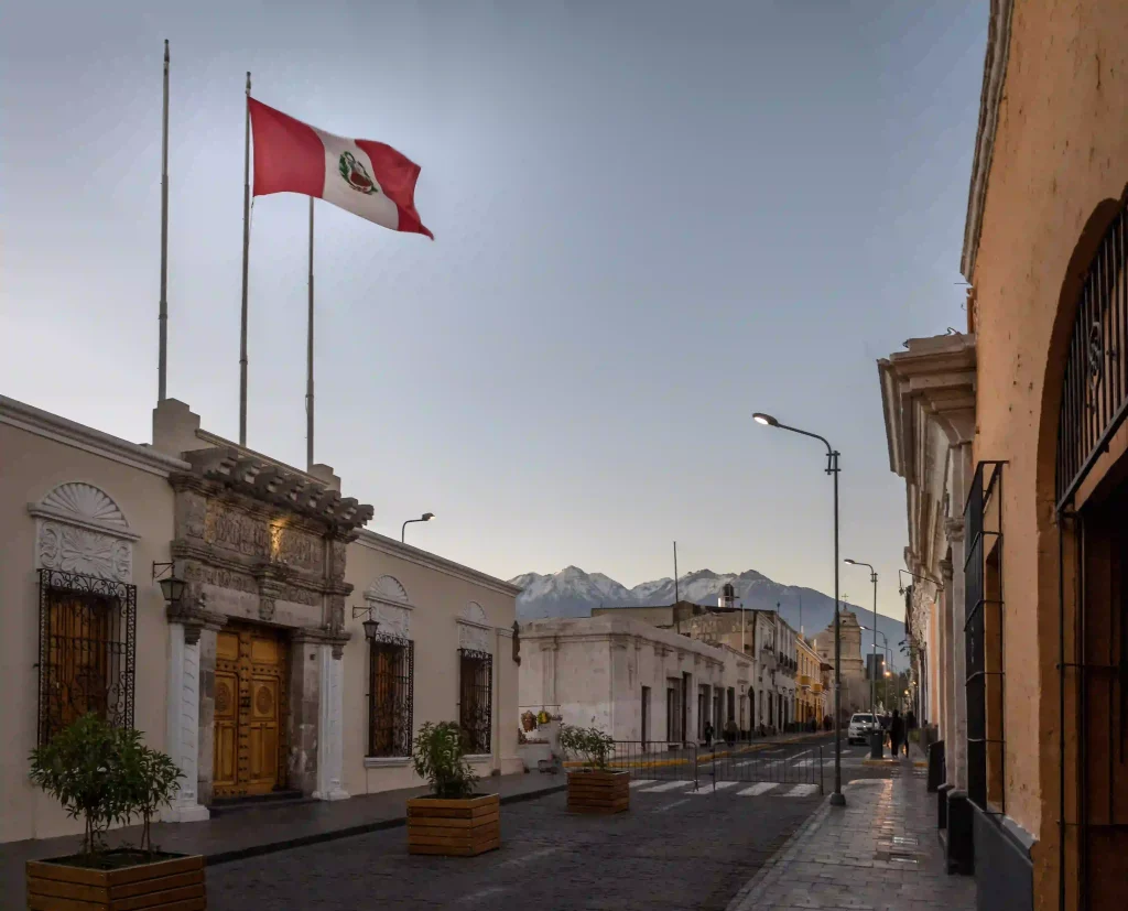 Calle típica peruana con las montañas de fondo y la bandera del pais ondeandose por el viento