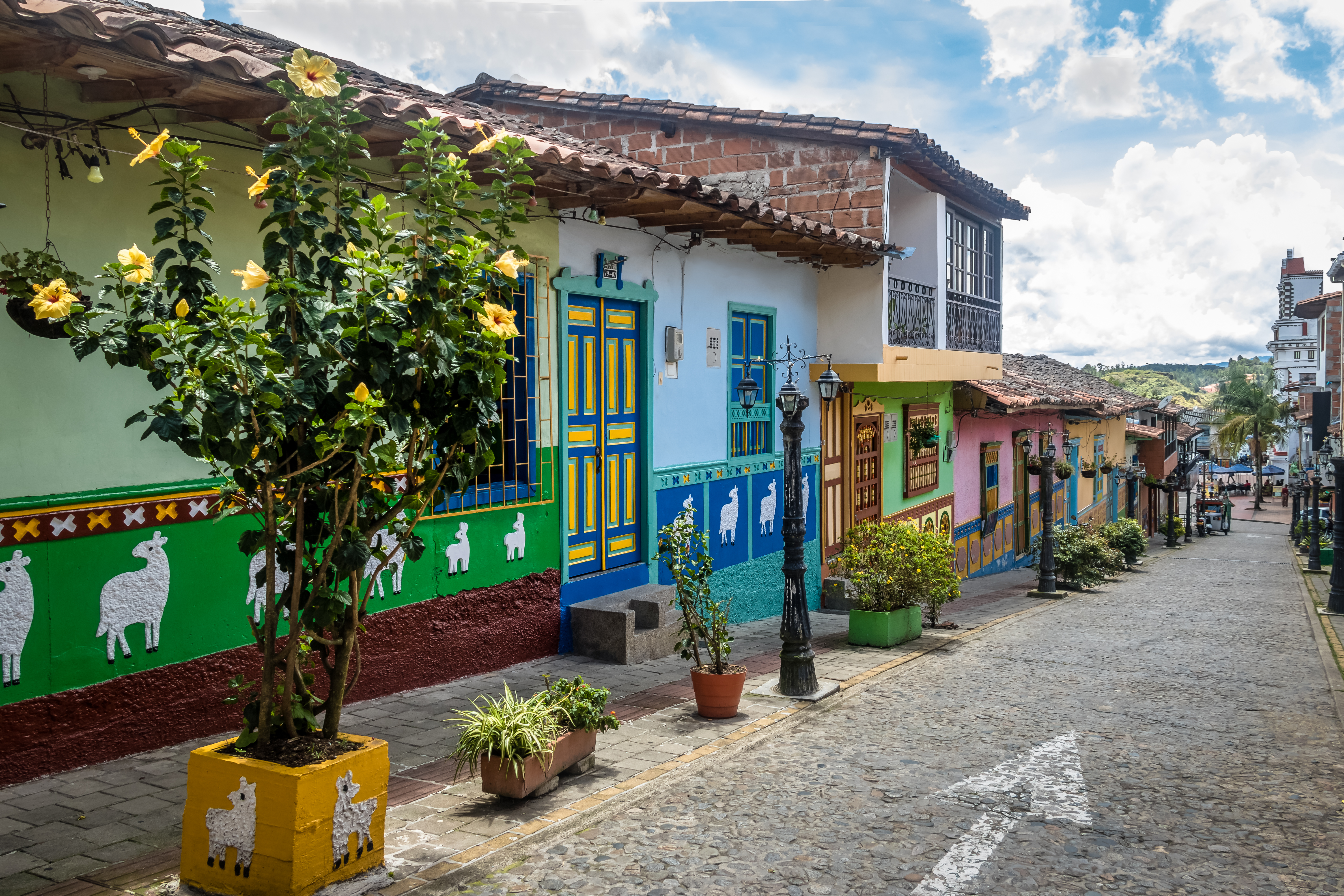 Casas coloridas en una calle empedrada en Guatapé, Antioquia, Colombia. Fachadas vibrantes decoradas con zócalos típicos reflejan la cultura y el encanto de este destino turístico.