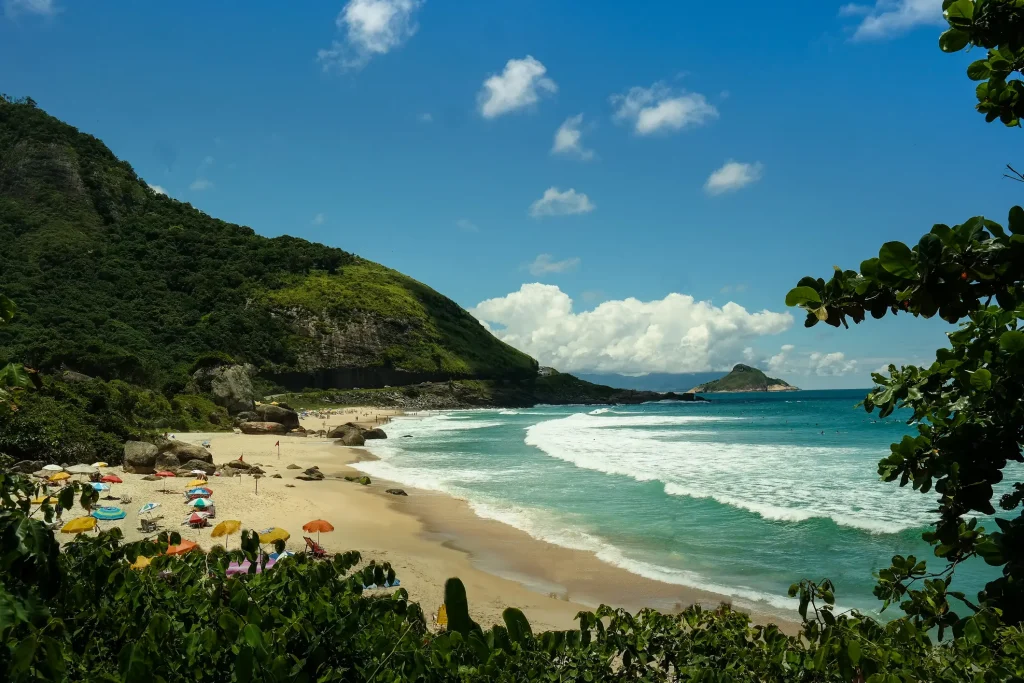The photo shows the sand and ocean of Prainha beach, along with the greenery that surrounds it.