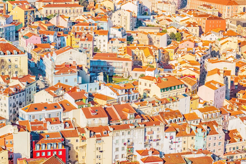 Foto das casas de telhados laranjas da cidade de Lisboa, em Portugal. A similaridade das construções fazem a foto ser incrível e registrar uma identidade da capital portuguesa.