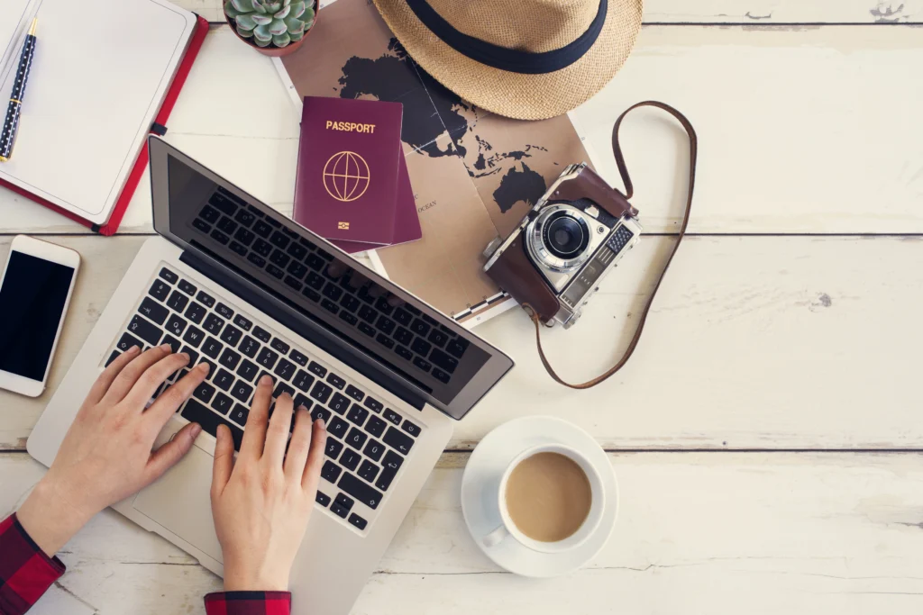 Foto de computador, pasaporte, diario y otras cosas necesarias para aprender cómo hacer un itinerario de viaje.
