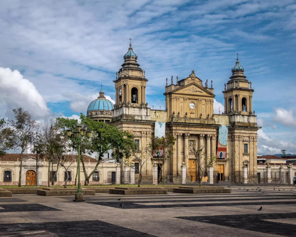 Foto de uma das construções mais icônicas da Cidade da Guatemala. O céu está azul e não há pedestres na rua.