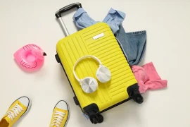 Maleta de viaje amarilla rodeada por otros objetos llevados en un viaje barato.