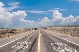 View of the famous Route 66 road with cracks and stretching to the horizon, above a blue sky