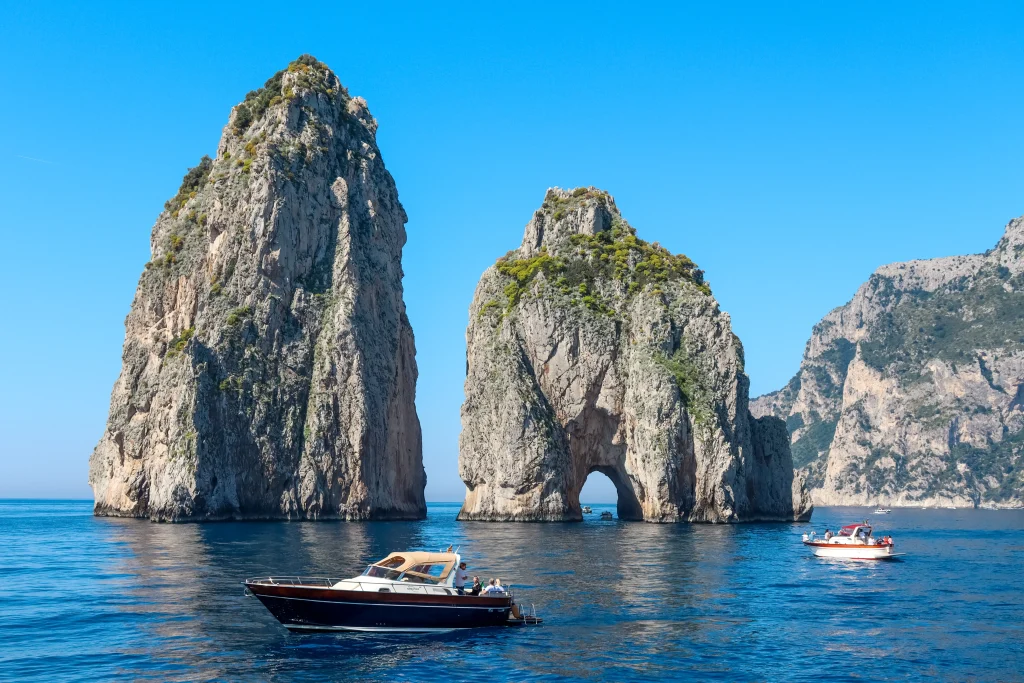 Three sea stacks, known as the Faraglioni, rise out of the Tyrrhenian Sea near the southern coast of Capri Island.