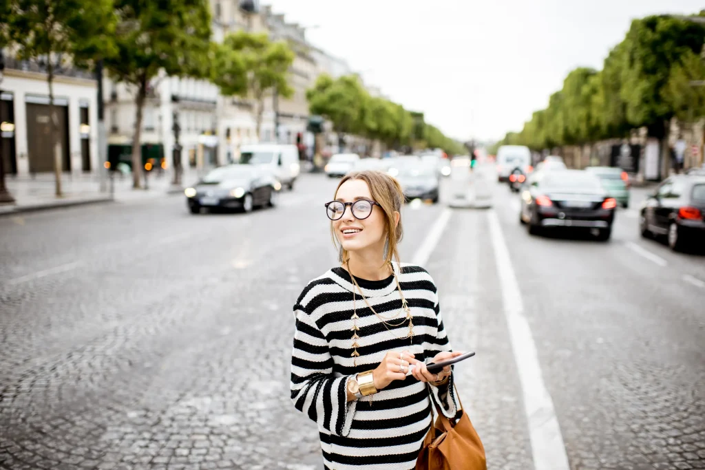 Mujer en medio a calles llenas de autos pensando en cuál de las ciudades cerca de París va a conocer.