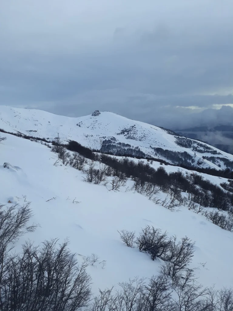 Uma imagem de um horizonte com montanha em neve em Bariloche e nuvens.