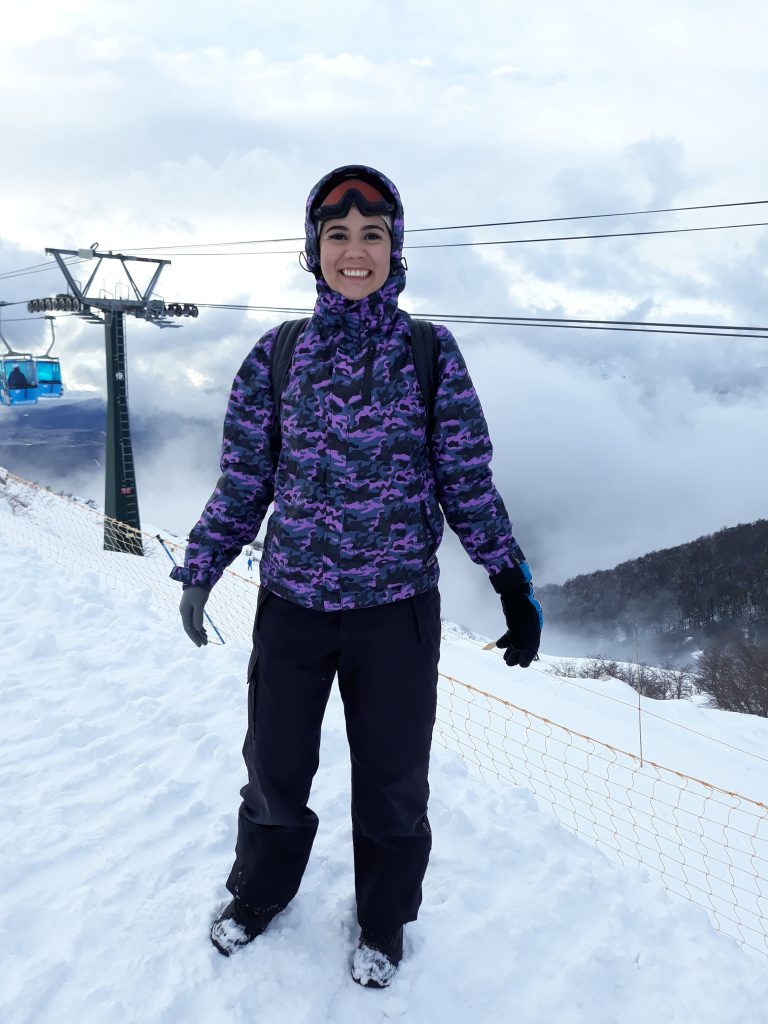 Uma mulher sorrindo com roupas apropriada para neve em estação de esqui em Bariloche.