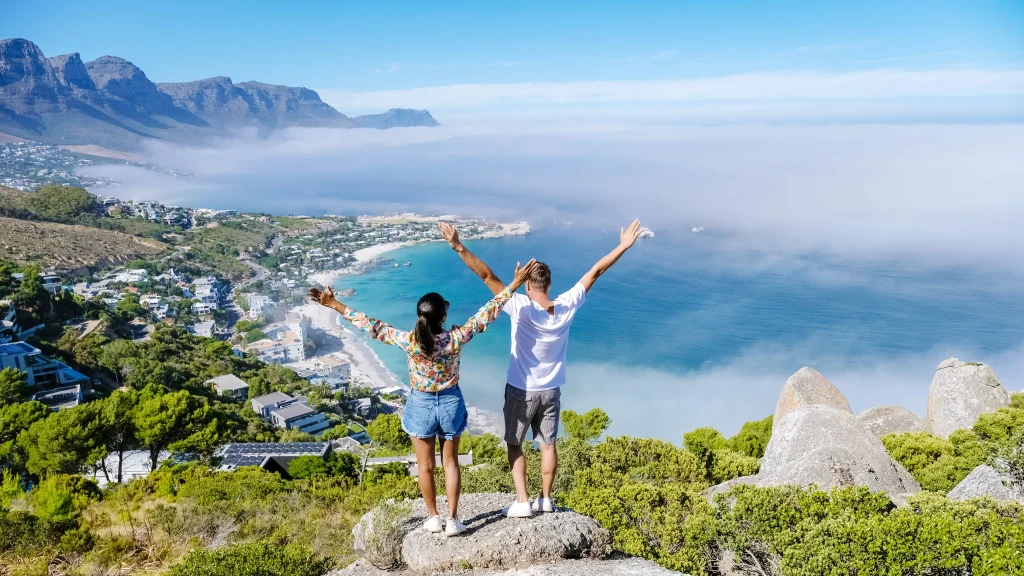 Um casal em cima de uma pedra olhando para uma paisagem da Cidade do Cabo.