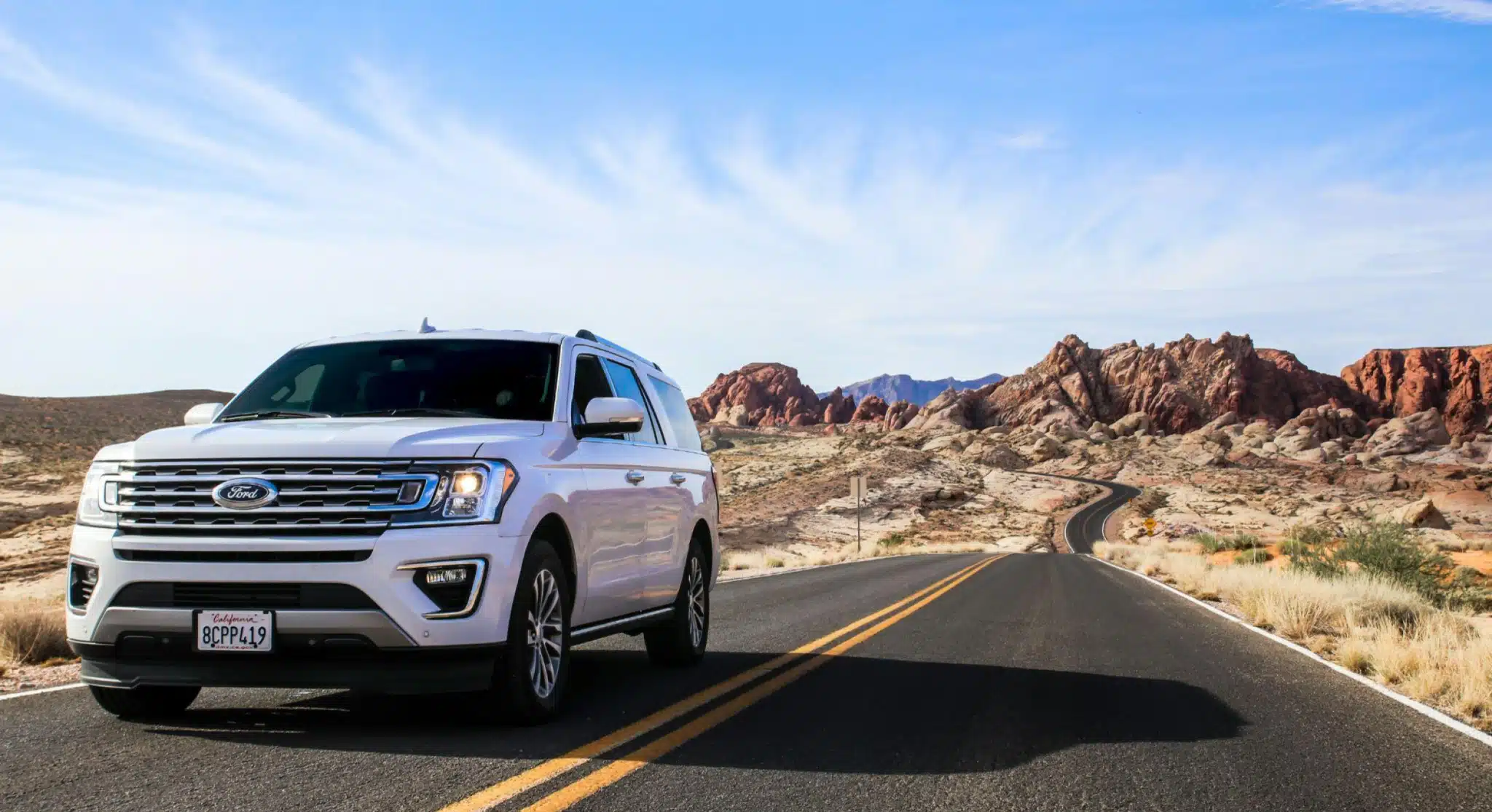 suv branca em um dia ensolarado em uma estrada com deserto ao lado