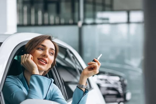 mulher sentada no carro segurando a chave com a cabeça para fora do vidro