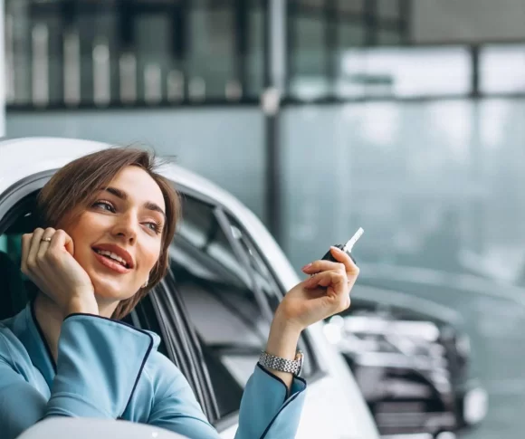 mulher sentada no carro segurando a chave com a cabeça para fora do vidro