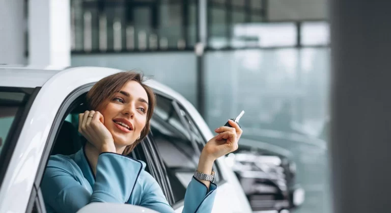 mulher sentada no carro segurando a chave com a cabeça para fora do vidro